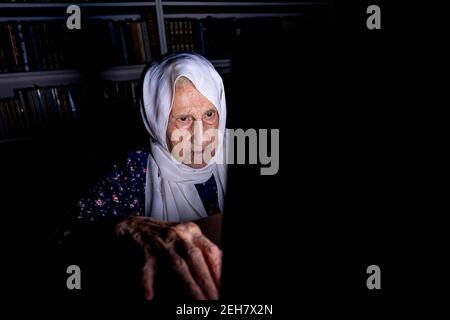 Alte Frau, die um Mitternacht im Dunkeln an ihrem Laptop arbeitet Zimmer Stockfoto