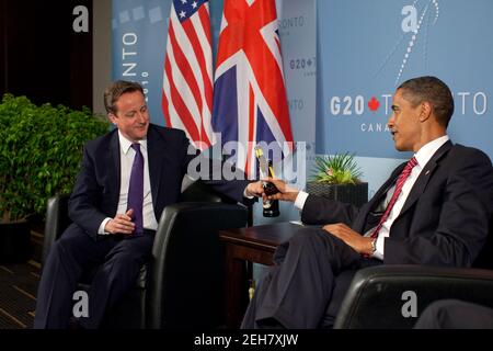 Präsident Barack Obama und der britische Premierminister David Cameron tauschen während eines bilateralen Treffens auf dem Gipfel G20 in Toronto, Kanada, am Samstag, den 26. Juni 2010, Flaschen Bier aus, um eine Wette auf das Fußballweltcup-Spiel USA gegen Großbritannien zu vereinbaren. Stockfoto