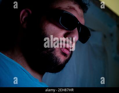 Arabischer Mann mit Sonnenbrille im dunklen Zimmer Stockfoto