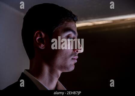 Arabischer Kerl im dunklen Raum mit Licht auf seinem Gesicht Und schöne Schatten Stockfoto