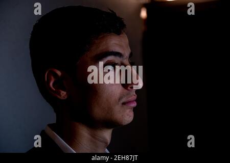 Arabischer Kerl im dunklen Raum mit Licht auf seinem Gesicht Und schöne Schatten Stockfoto