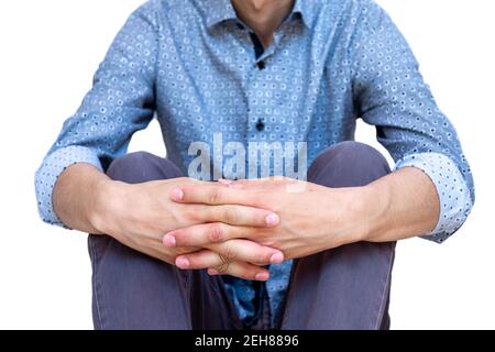 Kerl sitzt auf dem Boden und hält seine Beine mit seinen Hände Stockfoto