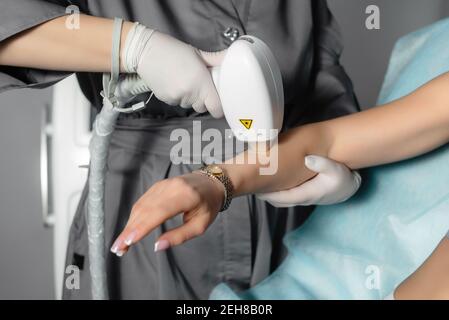 Kaukasische Frau mit Laser-Haarentfernung in professionellen Schönheitssalon. Laser Haarentfernung auf Client Hand. Laserepilation und Kosmetologie. Cosmetolog Stockfoto