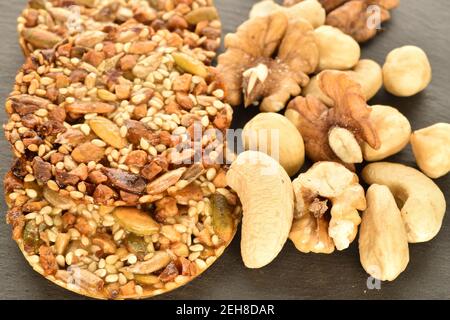 Mehrere ganze frische, duftende, köstliche nussige Kekse liegen zusammen mit natürlichen Nüssen, Nahaufnahme, auf einem Schiefertafel. Stockfoto