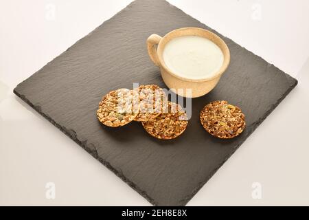 Mehrere ganze frische, duftende, köstliche Walnusskekse liegen auf einem Servierteller aus Schiefer, auf einem hellen Hintergrund, daneben ist eine leichte Keramikschale. Stockfoto