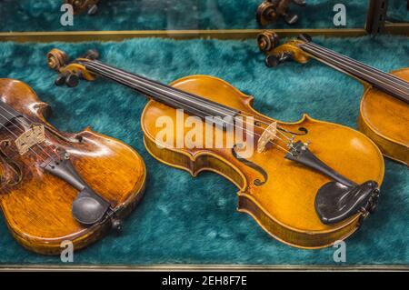 Ein paar alte antike Geigen auf dem Display in einem Glaskoffer zum Schutz noch intakt mit Patina innen getragen Stockfoto