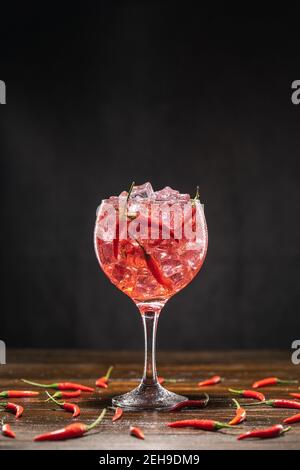 Roter Cocktail in einem Glas mit Eis und Chilischoten. Valentinstag-Konzept Stockfoto