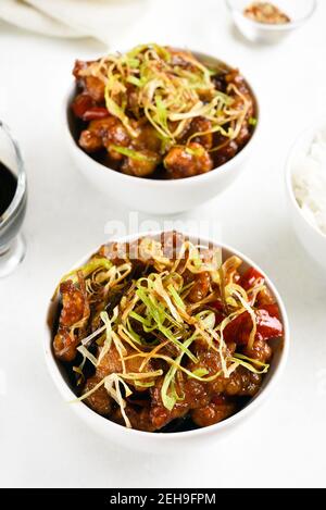 Würziger Knoblauch gebratenes Huhn (Kkanpunggi). Asiatische Huhn in süß-saure Sauce in Schüssel auf weißem Hintergrund. Nahaufnahme Stockfoto