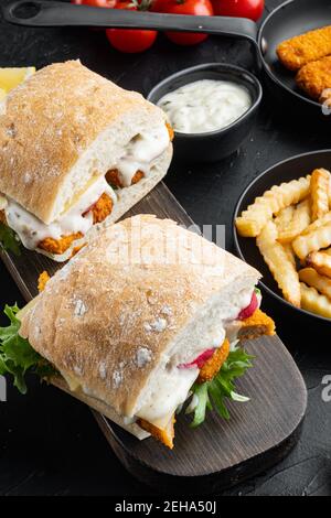 Fresh Made Snack Sandwich mit Fish Sticks Set, auf Holzschneidebrett, auf schwarzem Hintergrund Stockfoto