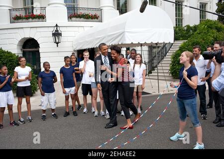 Präsident Barack Obama umarmt First Lady Michelle Obama, nachdem er ihr beim Sprung für eine doppelniederländische Demonstration während eines Tapings für die Presidential Active Lifestyle Award (PALA) Challenge und Nickelodeon's Worldwide Day of Play auf dem South Lawn des Weißen Hauses, 15. Juli 2011 zugesehen hatte. Stockfoto