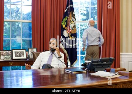 Vizepräsident Joe Biden schaut aus dem Fenster, während Präsident Barack Obama am Telefon mit dem Sprecher des Repräsentantenhauses John Boehner im Oval Office spricht, um die laufenden Bemühungen bei den Gesprächen über Schuldengrenze und Defizitabbau zu diskutieren, Sonntag, 31. Juli 2011. Stockfoto