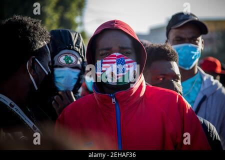 Tijuana, Mexiko. Februar 2021, 19th. Ein Migrant aus Haiti, der eine Maske in den Farben der mexikanischen und US-Flagge trägt, steht am Grenzübergang und wartet darauf, in den USA Asyl beantragen zu dürfen. Nach dem angekündigten Richtungswechsel in der US-Migrationspolitik haben sich zahlreiche Migranten an der Grenze zwischen Mexiko und den USA versammelt, in der Hoffnung, in die USA einzureisen. Mit der neuen Verordnung bricht die Regierung von US-Präsident Biden mit der restriktiven Einwanderungspolitik seines Vorgängers Trump. Quelle: Jair Cabrera Torres/dpa/Alamy Live News Stockfoto