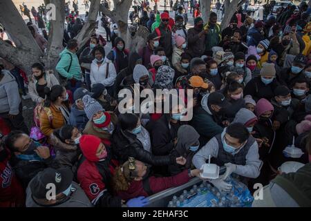 Tijuana, Mexiko. Februar 2021, 19th. Zahlreiche maskierte Migranten versammeln sich und warten auf die Verteilung von Nahrung und Wasser am Grenzübergang. Nach dem angekündigten Richtungswechsel in der US-Migrationspolitik haben sich zahlreiche Migranten an der Grenze zwischen Mexiko und den USA versammelt, in der Hoffnung, in die USA einzureisen. Mit der neuen Verordnung bricht die Regierung von US-Präsident Biden mit der restriktiven Einwanderungspolitik seines Vorgängers Trump. Kredit: Stringer/dpa/Alamy Live Nachrichten Stockfoto