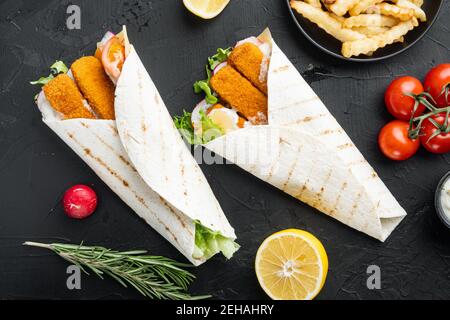 Tortilla Rolle mit Fischfinger, Käse und Gemüse Set, auf schwarzem Hintergrund, Draufsicht flach liegend Stockfoto