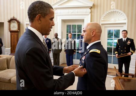 Präsident Barack Obama überreicht dem Militärstützpunkt des Weißen Hauses Oberstleutnant Barrett Bernard, US-Armee, während einer Abschiedszeremonie im Oval Office am 12. Oktober 2011 die Defense Superior Service Medal. Zusätzliche militärische Helfer stehen im Hintergrund. Stockfoto