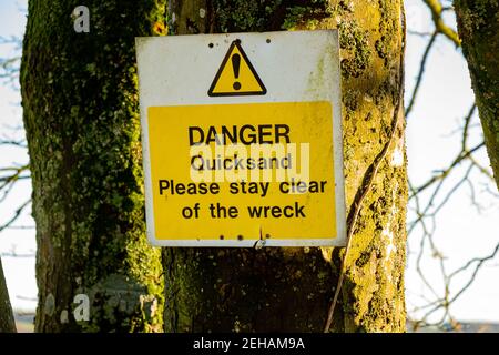 Gelbe Gefahr Treibsand, bitte sagen Sie frei von dem Wrackschild an einem Baum Stockfoto