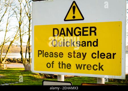 Gelbe Gefahr Treibsand, bitte sagen Sie frei von dem Wrackschild an einem Baum Stockfoto