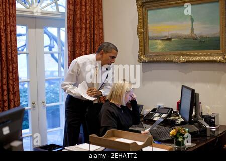 Präsident Barack Obama telefoniert mit Jon Favreau, dem Direktor für Sprechchriting, während er am Schreibtisch von Personal Aide Anita Decker im Outer Oval Office am 23. Januar 2012 einen Entwurf der Rede zur Lage der Union liest. Stockfoto