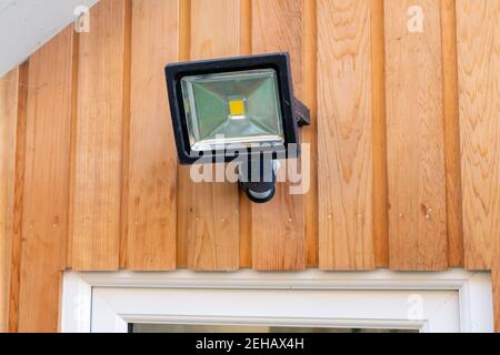 Gartenflutlicht an einer Holzwand darüber angebracht Eine Tür Stockfoto