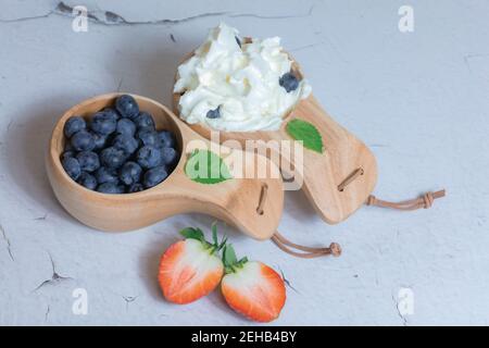 Frische Heidelbeeren und Erdbeeren mit Sahne in einem Holzbecher. Konzept natürliche Dissertation. Hochwertige Fotos Stockfoto