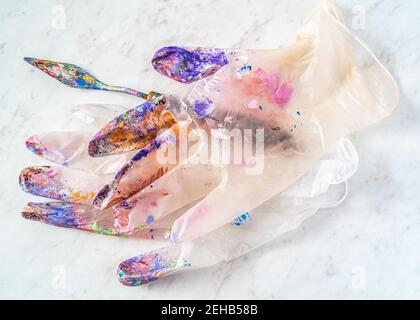 Handschuhe aus durchsichtigen Latex eines Künstlers, mit Farbspritzern überzogen. Stockfoto