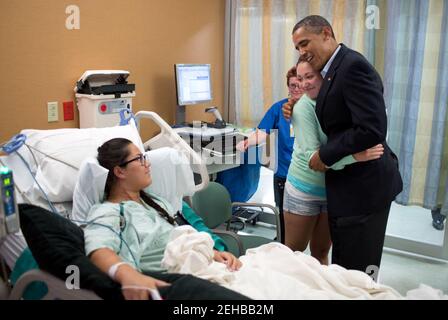 Präsident Barack Obama umarmt Stephanie Davies, die half, ihre Freundin Allie Young am Leben zu erhalten, nachdem sie während der Dreharbeiten im Kino in Aurora, Colorado, am 22. Juli 2012 gedreht wurde. Stockfoto