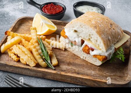 Burger mit Fischstäbchen frischer Salat, Tomate und Tartar-Sauce Set, auf grauem Hintergrund Stockfoto