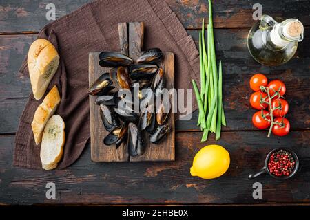 Miesmuscheln-Eintopf in Weißwein und Kräutern, auf Holzschneidebrett, auf altem dunklen Holztischhintergrund, Draufsicht flach liegend Stockfoto