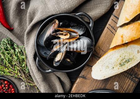 Klassische traditionelle gedünstete Muscheln in einem Weißwein in Schale, auf schwarzem Holztisch Hintergrund, Draufsicht flach legen Stockfoto