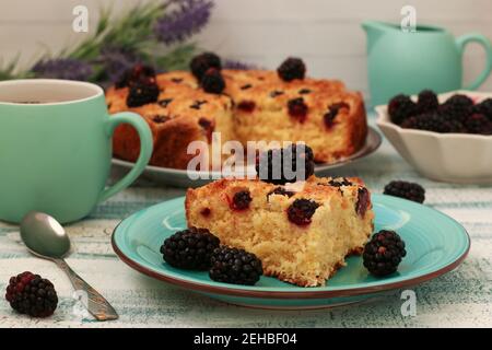 Piece hausgemachten Kuchen mit Brombeeren und Kokosnusschips auf einem hellblauen Hintergrund. Nahaufnahme Stockfoto