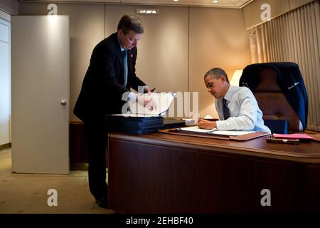 Präsident Barack Obama unterzeichnet Rechnungen an Bord der Air Force One während des Fluges nach Cleveland, Ohio, 5. Oktober 2012. Dem Präsidenten steht der Stabssekretär Doug Kramer zur Seite. Stockfoto