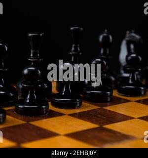 Schwarze Schachfiguren auf einem Schachbrett. Eine Armee von schwarzen Bauern auf dem Tisch. Stockfoto