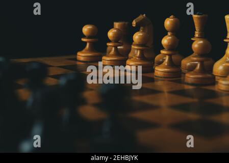 Schwarze Schachfiguren gegen weiße Schachfiguren auf einem Schachbrett. Stockfoto