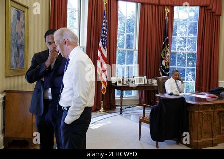 Vizepräsident Joe Biden spricht mit Rob Nabors, dem stellvertretenden Stabschef für Politik, links, während Präsident Barack Obama am Telefon mit dem französischen Präsidenten François Hollande über Syrien im Oval Office spricht, Samstag, 31. August 2013. Stockfoto