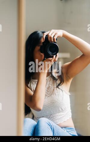 Langhaarige Brünette Frau, die in den Spiegel schaut Stockfoto
