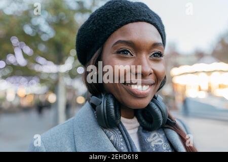Nahaufnahme afroamerikanische weibliche aufstehen in Oberbekleidung Straße und Mit Kopfhörern Stockfoto