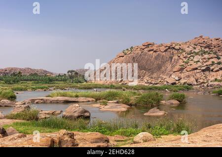 Anegundi, Karnataka, Indien - 9. November 2013: Navabrindavana Insel und Tempel. Breite Tungabhadra Flusslandschaft mit vielen grünen Bäumen und Unkraut ar Stockfoto