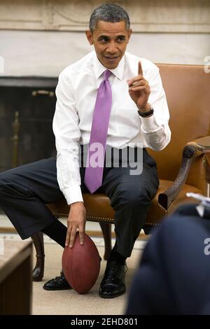 Präsident Barack Obama hält einen Fußball, während er mit hochrangigen Beratern im Oval Office, 11. Dezember 2013 trifft. Stockfoto