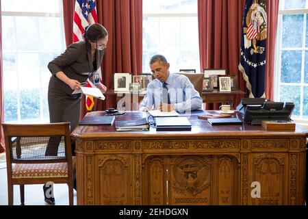 Präsident Barack Obama unterzeichnet zusammen mit dem Stabssekretär Joani Walsh Gesetzesvorlagen im Oval Office, 21. März 2014. Stockfoto