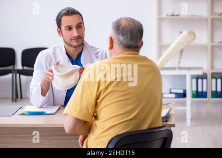 Alter Hals verletzten Mann besucht jungen Arzt Stockfoto