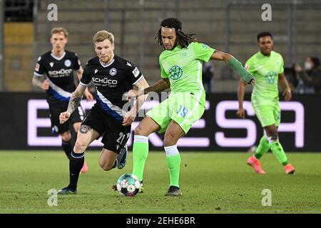 Bielefeld, Deutschland. Februar 2021, 19th. Kevin Mbabu (R) aus Wolfsburg steht mit Andreas Voglsammer aus Bielefeld während eines Bundesliga-Fußballspiels zwischen DSC Arminia Bielefeld und VfL Wolfsburg am 19. Februar 2021 in Bielefeld auf dem Spiel. NUR FÜR REDAKTIONELLE ZWECKE. DEUTSCHLAND AUS. Quelle: Ulrich Hufnagel/Xinhua/Alamy Live News Stockfoto