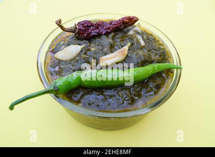 Indisches hausgemachtes Curry Sarson ka saag KI sabji serviert in transparenter Schüssel garniert mit gebratenen grünen kühlen, roten kühlen und Knoblauchzehen. Authentisch Nein Stockfoto