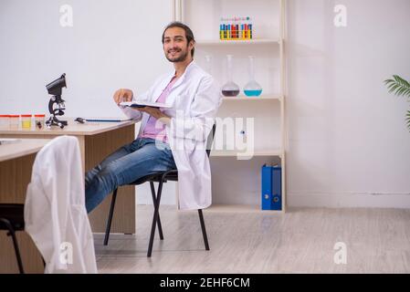 Junge Chemikerin, die im Klassenzimmer am Schreibtisch sitzt Stockfoto