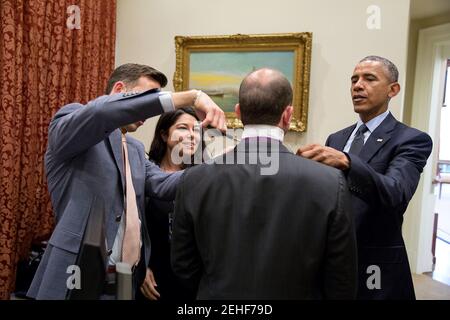 Präsident Barack Obama, Brian Mosteller, Director des Oval Office Operations und persönlicher Adjutant Ferial Govashiri helfen Ben Rhodes, stellvertretender nationaler Sicherheitsberater für strategische Kommunikation mit seiner Krawatte im äußeren Oval Office, 17. April 2015. Stockfoto