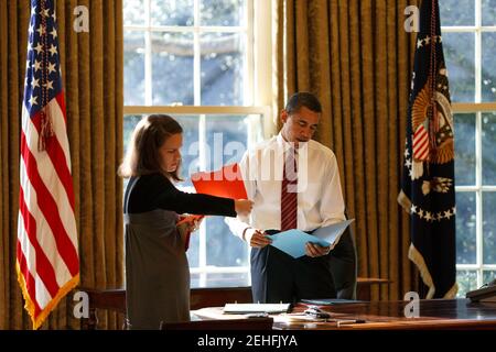 Präsident Barack Obama betrachtet die tägliche Korrespondenz mit seiner persönlichen Sekretärin Katie Johnson im Oval Office, 30. Januar 2009. Stockfoto