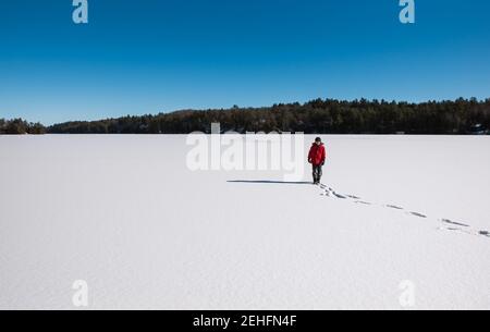 Kleiner Junge, der allein in der Mitte eines gefrorenen verschneiten Sees steht. Stockfoto