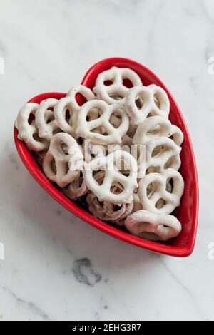 Frische Schokolade und Joghurt getauchte Brezeln in Valentinstag Herz Stockfoto