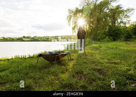 Angeln Adventures, Karpfen angeln. Angler, bei Sonnenuntergang, ist die Fischerei mit Karpfen angeln Technik. Camping am Ufer des Sees. Stockfoto