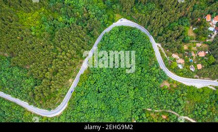 Luftaufnahme der kurvenreichen Straße durch die dichten Wälder auf dem hohen Berg in Bulgarien. Stockfoto