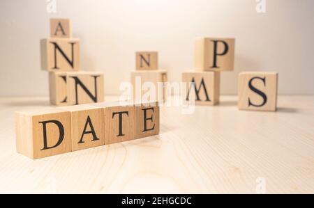 Das Wort Datum besteht aus Holzwürfeln. Hintergrund aus Holzbuchstaben. Nahaufnahme. Stockfoto